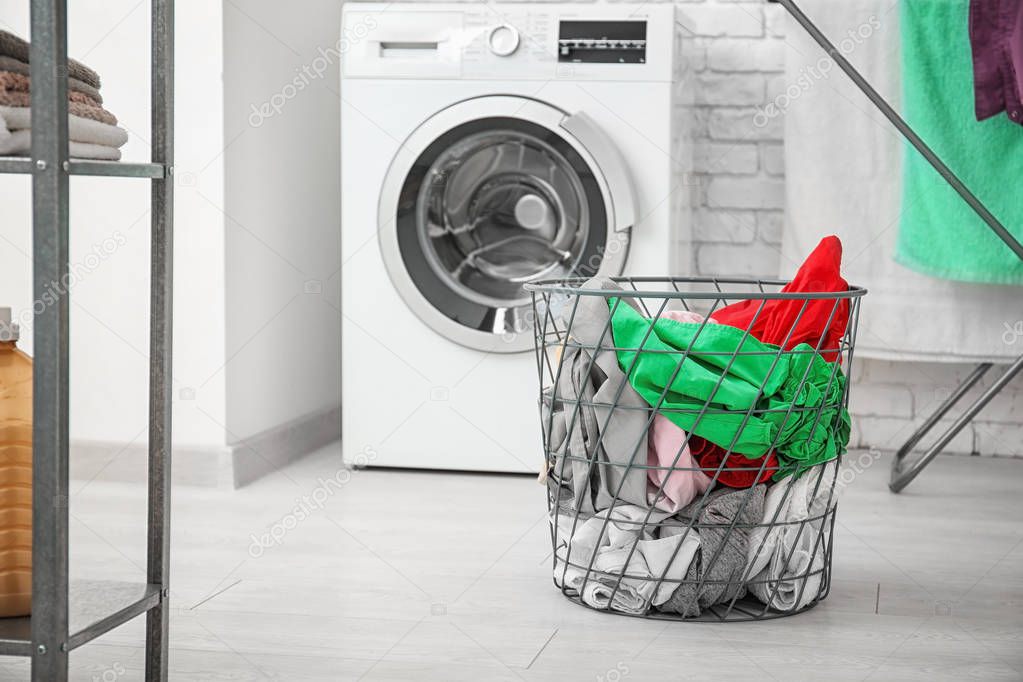 Basket with laundry and washing machine in bathroom