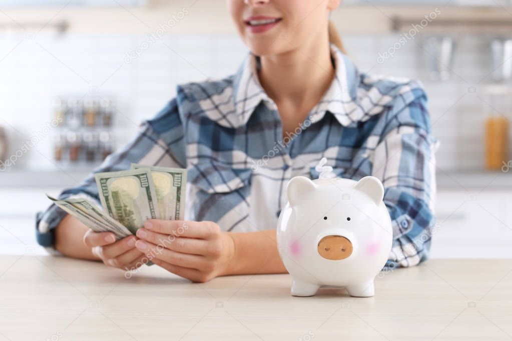Woman with piggy bank and money at table, closeup
