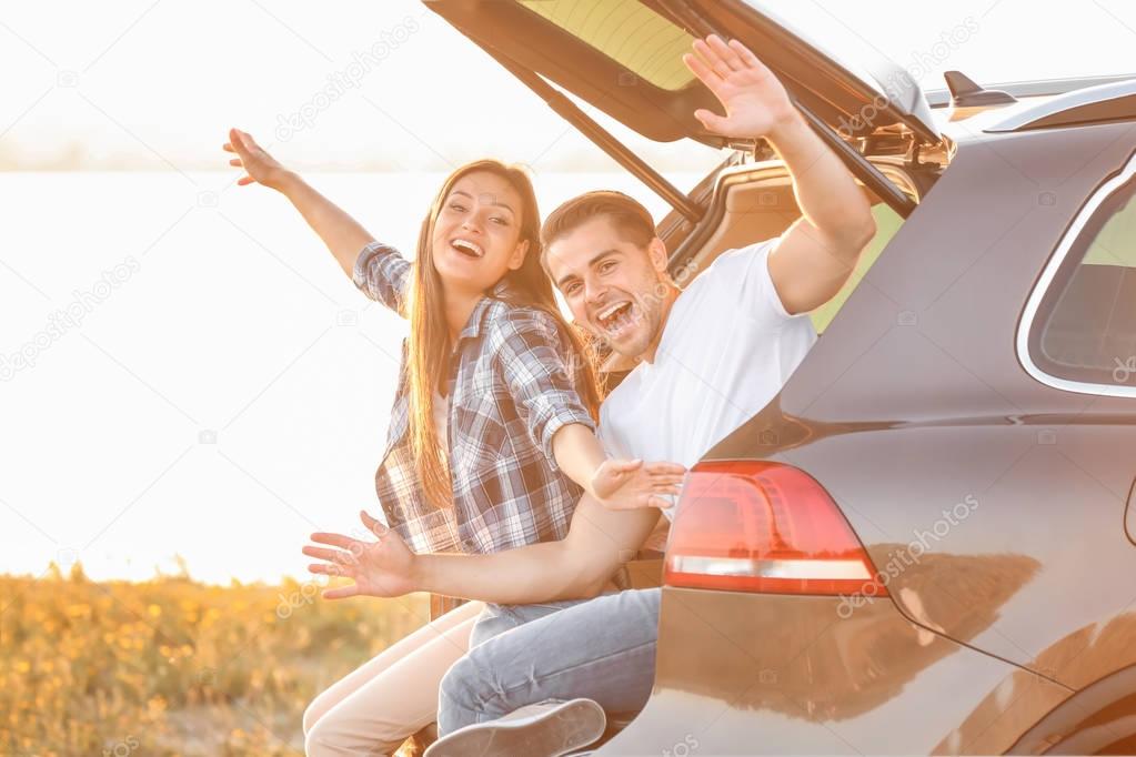 Beautiful young couple sitting in car  trunk