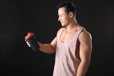 Sportif genç adam protein sallamak siyah arka plan üzerine