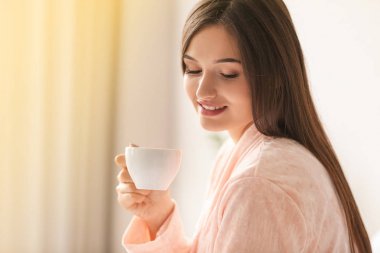 Genç bayan evde kahve içiyor.