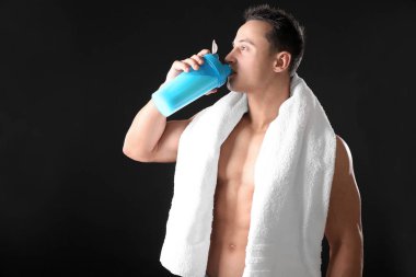 Siyah arka plan üzerine Protein içeceği içmeye sportif genç adam