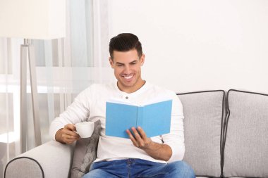 Yakışıklı adam evde koltukta istirahat ederken kitap okuma