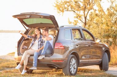 Güzel genç çift alarak selfie araba gövde