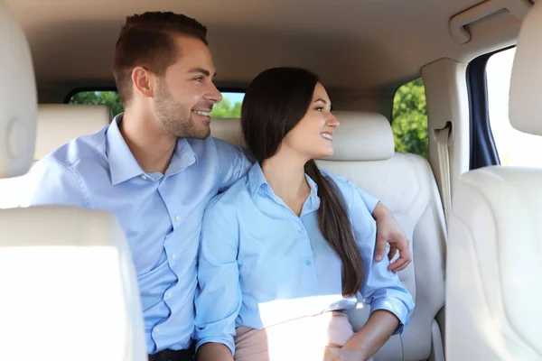 Bonito jovem casal sentado no banco de trás no carro — Fotografia de Stock