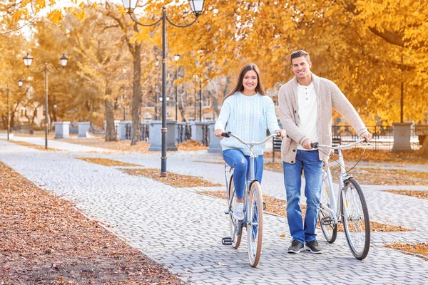 Young couple riding bicycles in park