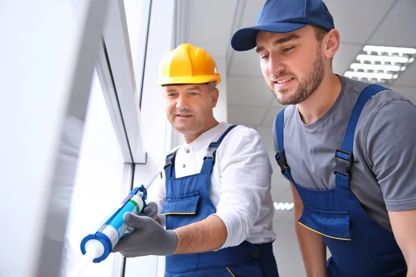 Construction worker with trainee installing window in house — Stock Photo, Image