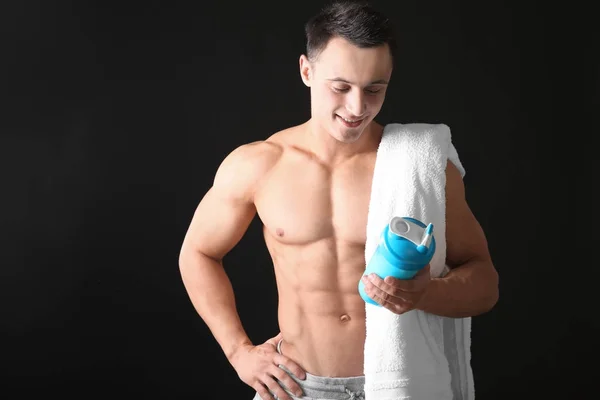 Sporty young man with protein shake on black background