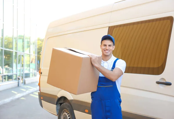 Delivery man with moving box near car — Stock Photo, Image