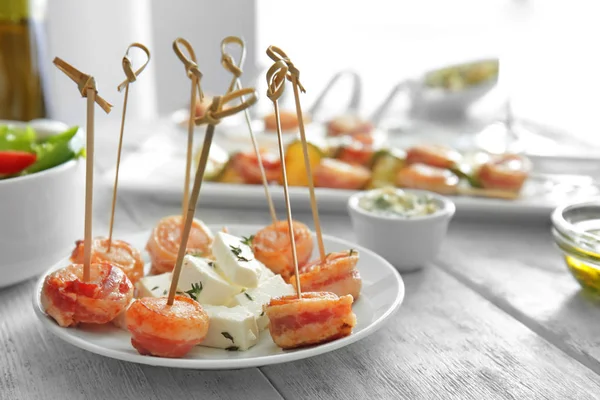 Placa con vieiras envueltas en tocino en la mesa — Foto de Stock