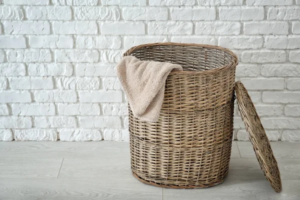Плетений кошик з білизною на підлозі проти цегляної стіни — стокове фото