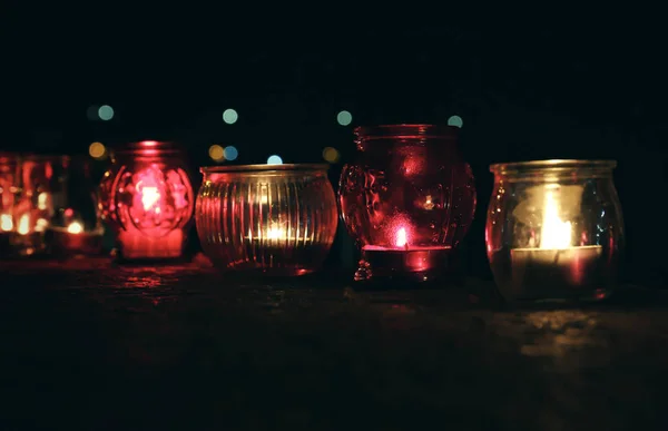 Frascos con velas encendidas en la superficie de piedra en la oscuridad — Foto de Stock