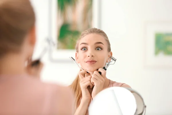 Jeune femme émotionnelle avec friseur de cils — Photo