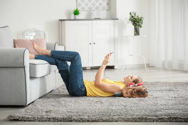 Красива жінка слухає музику, відпочиваючи на підлозі вдома — стокове фото