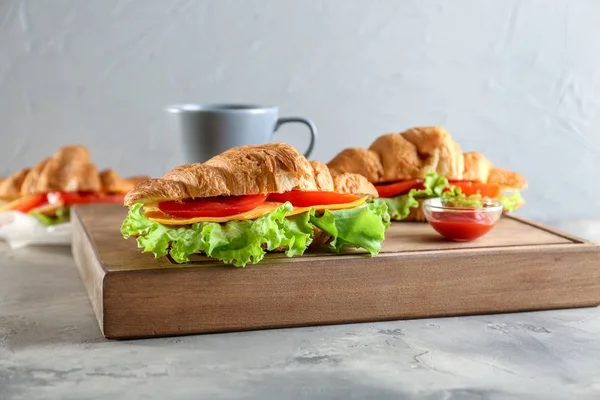 Placa de madeira com deliciosos sanduíches de croissant — Fotografia de Stock