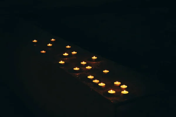 Lots of burning candles in darkness — Stock Photo, Image