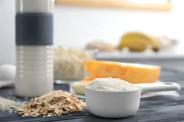 Scoop with protein powder and products on table