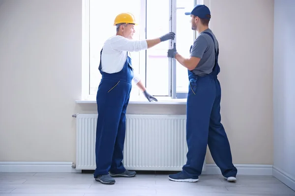 Construction worker with trainee installing window in house — Stock Photo, Image