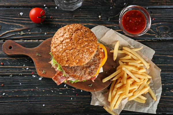 Board with tasty double burger on wooden table — Stock Photo, Image