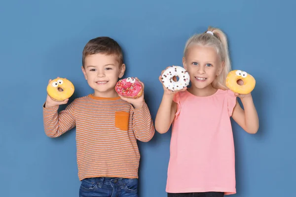 带甜甜甜圈的小孩子在颜色背景 — 图库照片