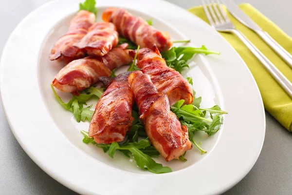 Plate with bacon wrapped chicken nuggets on table, closeup