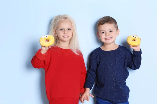 带甜甜甜圈的小孩子在颜色背景 — 图库照片