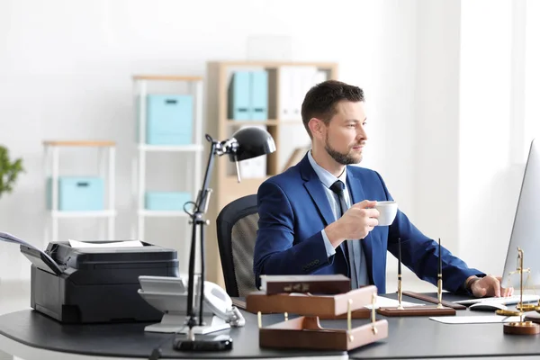 Junger männlicher Notar trinkt Kaffee im Büro — Stockfoto