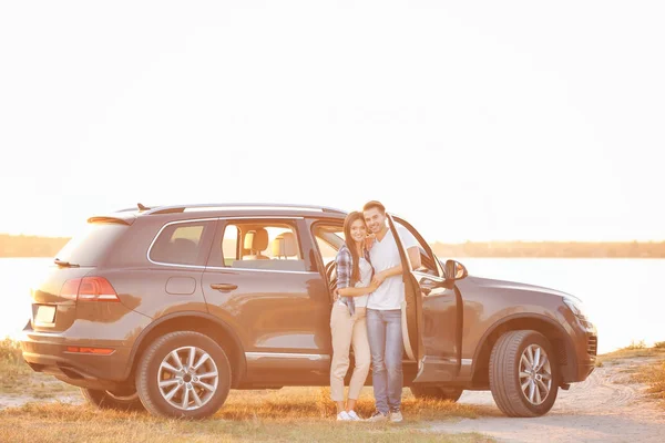 Bonito jovem casal de pé perto do carro — Fotografia de Stock