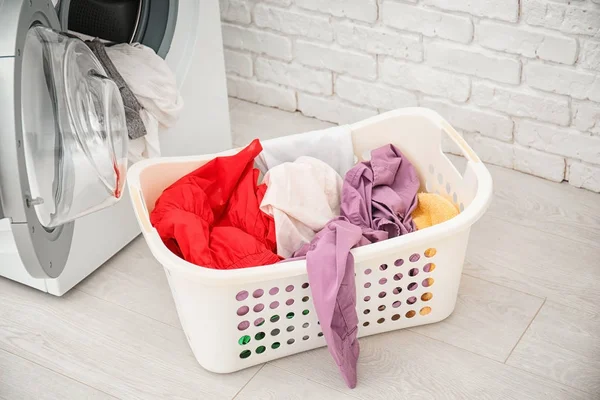 Basket with laundry and washing machine in bathroom