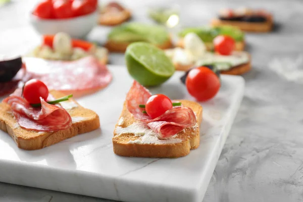Leckere Sandwiches mit Salami und Kirschtomaten an Bord, Nahaufnahme — Stockfoto