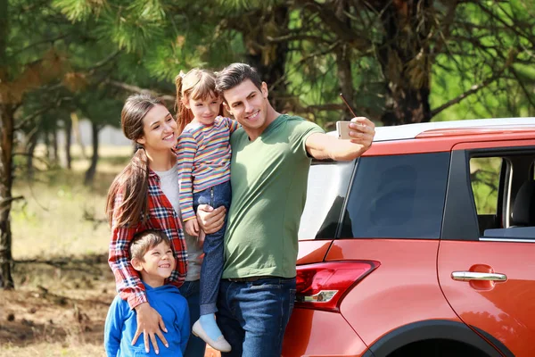 Šťastná rodina pořizování selfie poblíž moderní auto venku — Stock fotografie