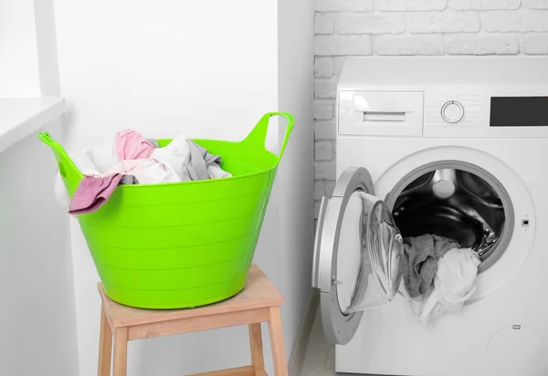 Mand met Wasserij op kruk en wasmachine in de badkamer — Stockfoto