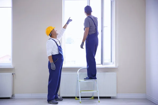 Construction worker with trainee installing window in house — Stock Photo, Image