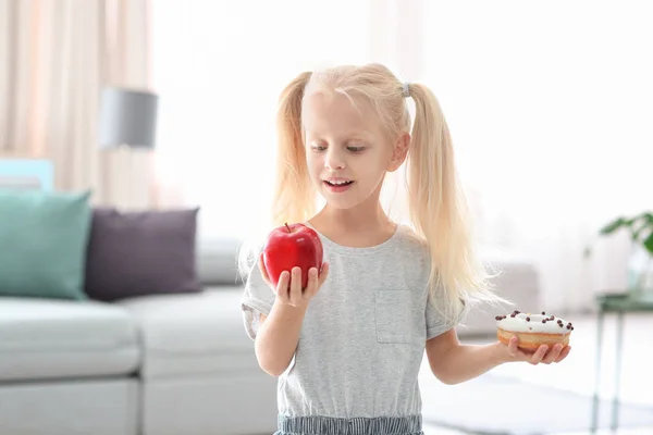 甜甜的甜甜圈和新鲜的苹果在房间里的小女孩 — 图库照片