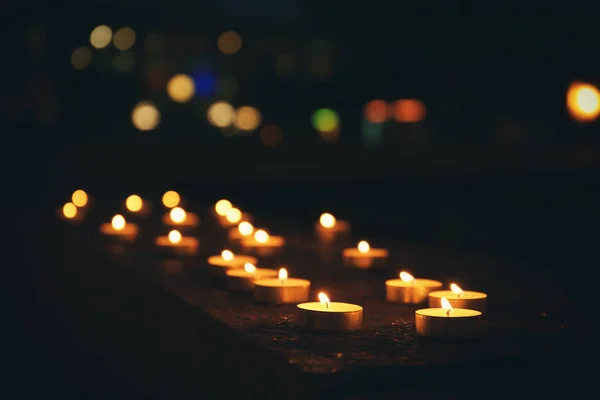 Багато палаючих свічок у темряві — стокове фото