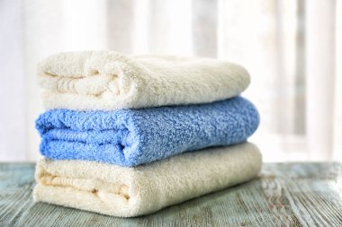 Stack of bath towels on table against light background clipart