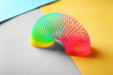 Rainbow slinky on color background. Toy for kids clipart