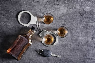 Gri arka plan üzerinde alkol, kelepçe ve araba anahtarı ile kompozisyon. Yok içki ve sürücü kavramı