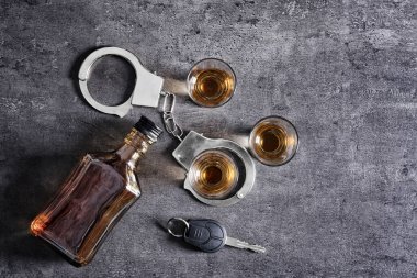 Composition with alcohol, handcuffs and car key on grey background. Don't drink and drive concept clipart