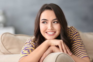 Genç güzel gülümseyen kadın evde koltukta dinleniyor