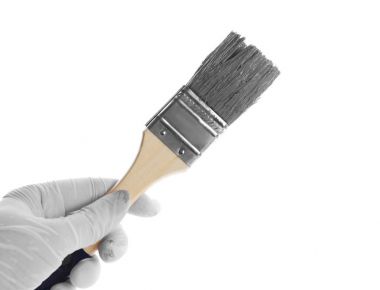 Beyaz arka planda gri boya batırılmış fırça tutan kadın