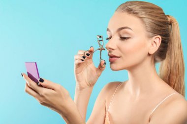 Güzel genç kadın kirpik kıvırıcı renk arka plan üzerinde kullanma