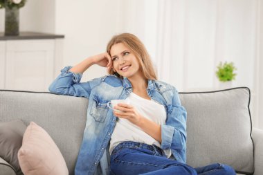 Güzel kadın evde koltukta istirahat ederken kahve içme