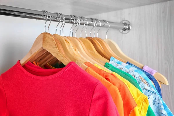 Πολύχρωμα ρούχα σε κρεμάστρες στην ντουλάπα — 图库照片