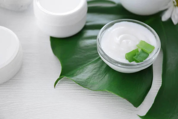Bowl with body cream and aloe leaves on table — Stock Photo, Image