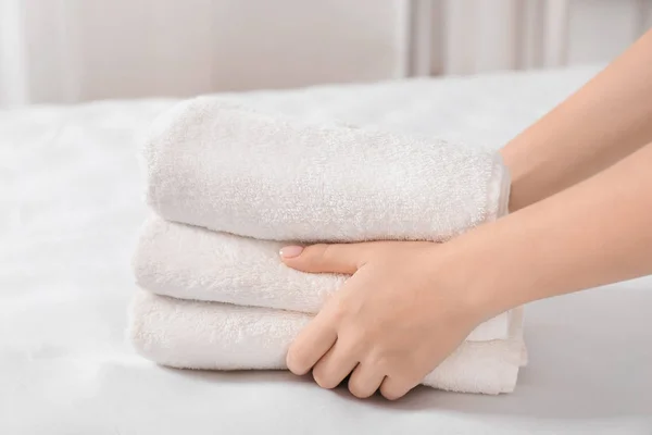 Woman putting stack of towels on bed — Stock Photo, Image