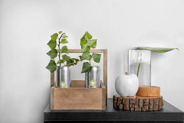 锡罐与植物在桌附近轻的墙壁 废物回收概念 — 图库照片