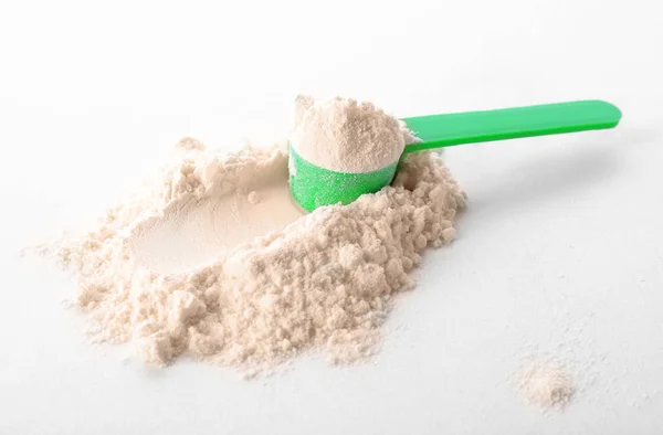 Measuring scoop and protein powder on white background