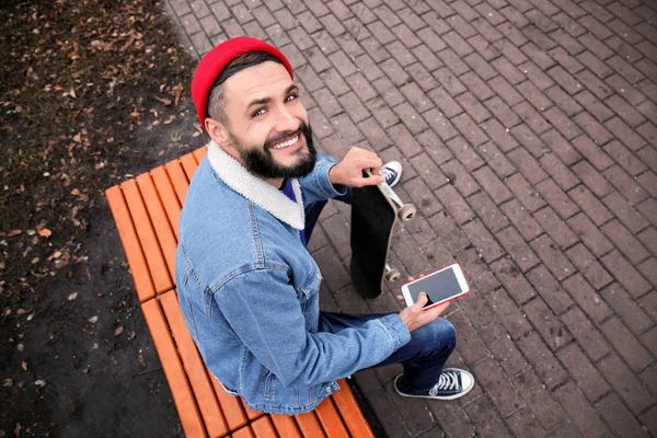 Aantrekkelijke Jonge Hipster Met Mobiele Telefoon Rusten Bank Buitenshuis — Stockfoto