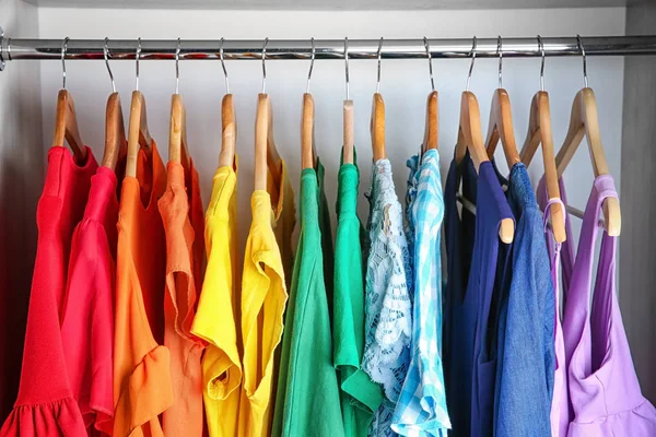 Colorful clothes on hangers in wardrobe — Stock Photo, Image